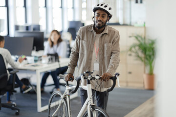 Businessman walking bicycle in office