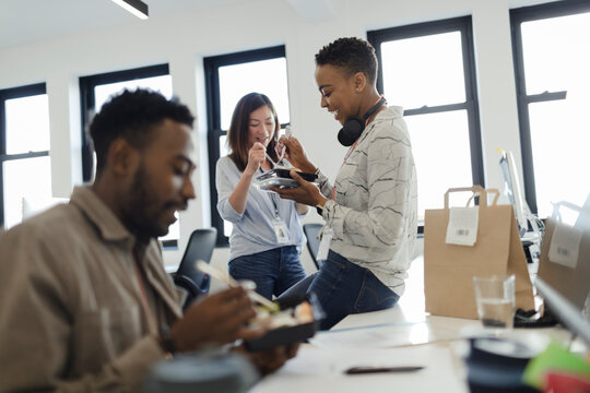 Business people eating takeout lunch at desk in office