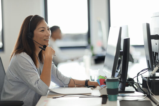 Smiling businesswoman in headset working at computer in office