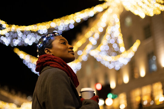 Serene young woman with coffee in city with lights at night - Powered by Adobe