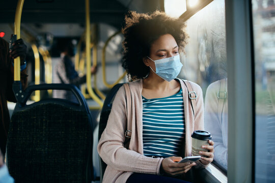 Distraught African American woman wearing face mask while traveling by public transport.