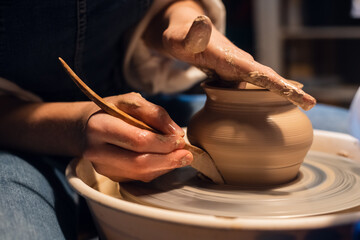 close-up of the hands of a Potter when sculpting a vase from clay on a potter's wheel in the workshop