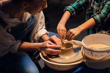 a young mother teaches her son the family pottery craft in a workshop