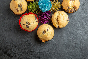 New year decorations around small cupcakes with chocolates on dark background