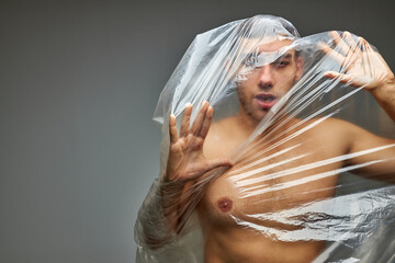 young man with plastic bag on half-naked body, can not get rid of it, global world pollution,...