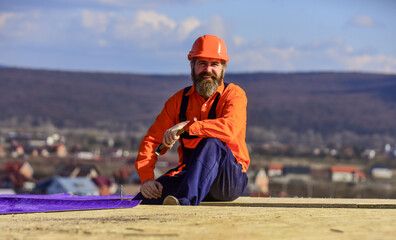in work clothes. roofer working on roof structure of building on construction site. roofer wear...