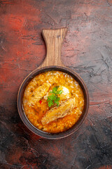 top view chicken soup in wood bowl with handle on dark red ground with copy space