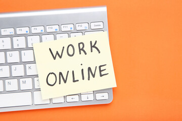 Inscription Work Online on paper with keyboard on orange background