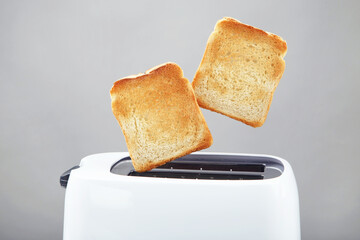 Toasts jumping out of the toaster on grey background