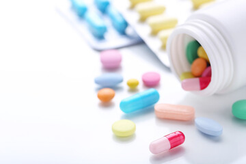 Colorful pills and bottle on white background