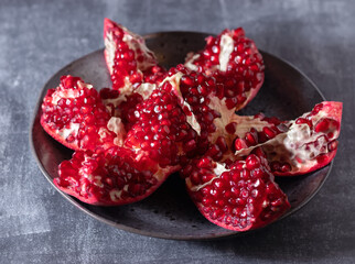 Juicy pomegranate split into pieces on a plate.