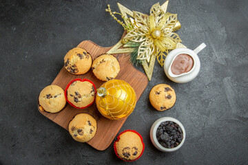 Tea break with delicious small cupcakes black raisins and chocolate in a white pot on black background