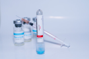 Testing for presence of coronavirus. Tube containing a swab sample that has tested positive for COVID-19. A single bottle vial of Covid-19 coronavirus vaccine in a research medical lab. 