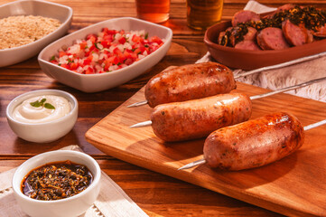 BBQ grilled pork sausage skewers on wood cutting board with chimichurri