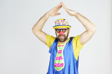 Clown - a man in a bright blue and yellow suit, glasses and a hat emotionally raised his hands up.