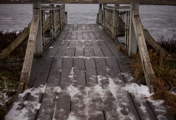 Obraz premium wooden pier on the frozen river Bank on a Sunny winter day