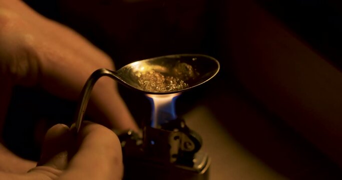 Cooking heroine in a spoon over an open flame. Drug abuse and opiate addicts
