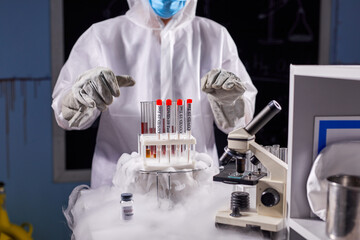 professional researcher is doing experiment with smoke on a table of a chemical laboratory, using test coronavirus tubes, conduct scientific experiment