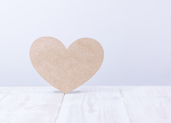 plywood heart on a white wooden table against a light wall
