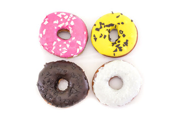four traditional American donuts with chocolate, pink, yellow, white icing and sprinkles isolated on a white