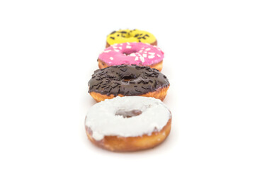 row of traditional American donuts with chocolate, pink, yellow, white icing and sprinkles isolated on white background. Copy space.