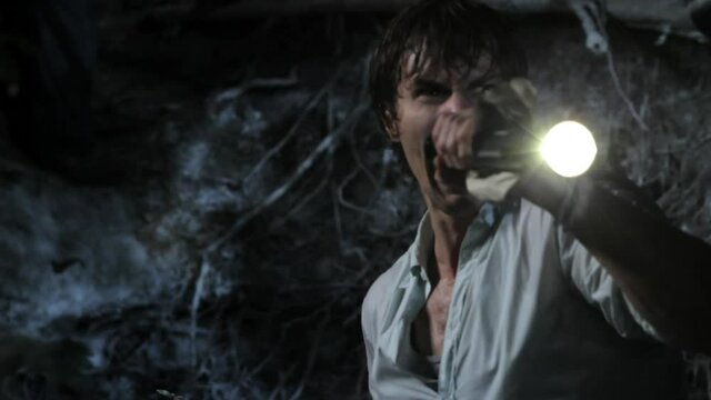 Man holding flashlight in woods at night screaming and shaking in fear