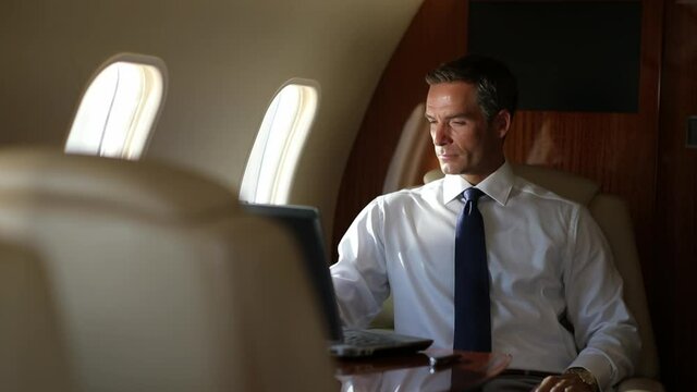 Caucasian businessman working on laptop on private jet