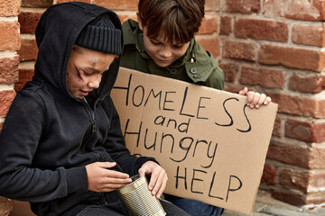 street child boy looks at bank with donation money, want to buy some food, sitting on street