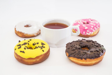 cup of tea and traditional American donuts with chocolate, pink, yellow, white icing and sprinkles on a white background. Side view.