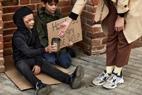 unrecognizable woman help children beggars, give some money, on city streets