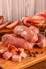 Raw brazilian bacon sausages on the wooden board with fresh cubes of bacon and spices - Linguiça de bacon