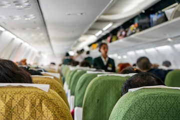 Commercial plane interior before take off, focus on man head at seat ahead, most of passengers...