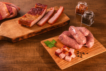 Raw brazilian bacon sausages on the wooden board with fresh cubes of bacon and spices - Linguiça de bacon