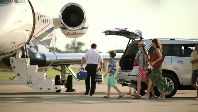 Caucasian pilot photographing family on tarmac near private jet