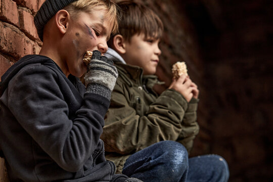 little helpless children eating food given by strangers on street in big city, caucasian kids suffer from poverty, having no home and parents