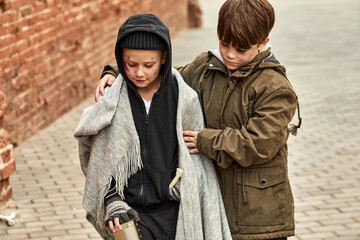 two despaired street boys support each other, begging in city streets, at cold weather