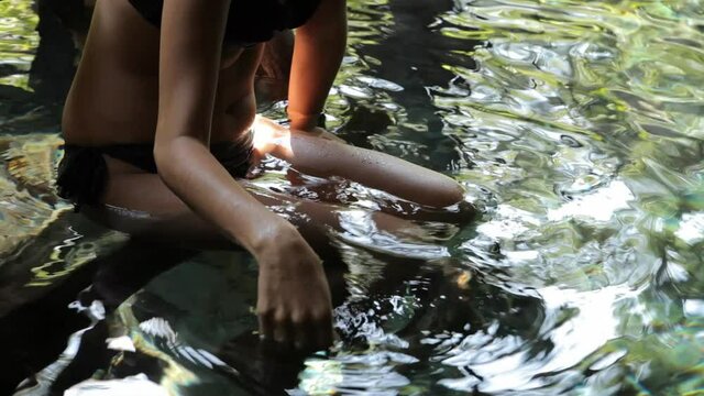 Woman slowly dragging hand back and forth through water