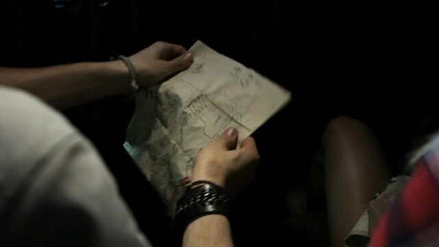 Over the shoulder view of couple reading map in car at night