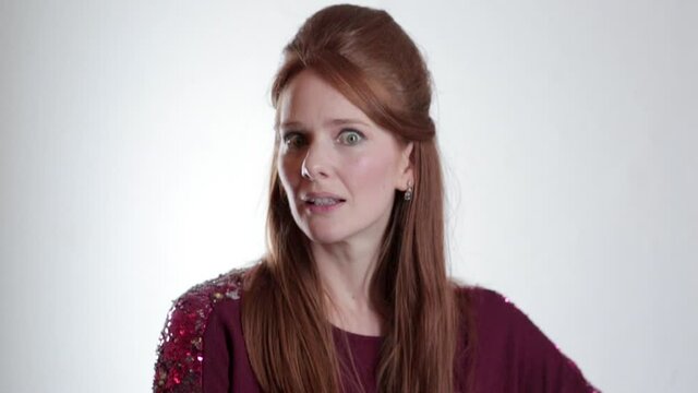 A young redheaded comedian making funny faces against a white background.