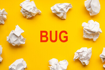 Bug text on yellow background with copy space. Crumpled sheets of paper lie around. Business concept image