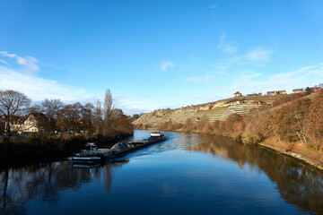 A boat is coming down the river neckar in the vineyards in Stuttgart at an autumn day 