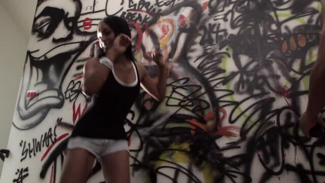 Women dancing in front of graffiti wall at house party