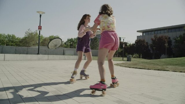 Slow motion of girls holding hands and spinning on roller skates / Salt Lake City, Utah, United States