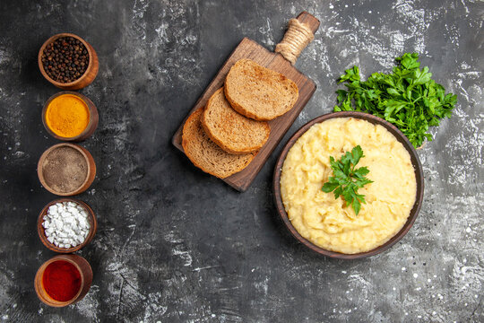 Top View Mashed Potatoes Species In Small Bowls Parsley Bread Slices On Cutting Board On Dark Background With Copy Space