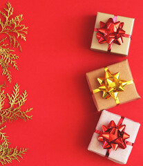 DIY handmade Christmas gift boxes in craft paper. Boxes on a red background and golden sprigs on a red background. Copy spase