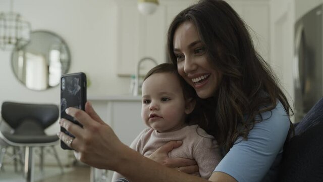 Slow motion of mother with baby daughter video conferencing on cell phone / Bluffdale, Utah, United States