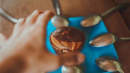 hand trying to catch a cupcake on a wooden background