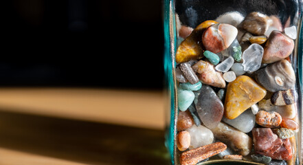 Glass bottle half full of rounded pebbles and rocks