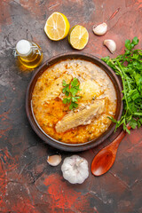 top view chicken soup garlic wooden spoon oil parsley lemon slices on dark red background