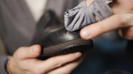Male cobbler explains how to polish shoes using cloth
